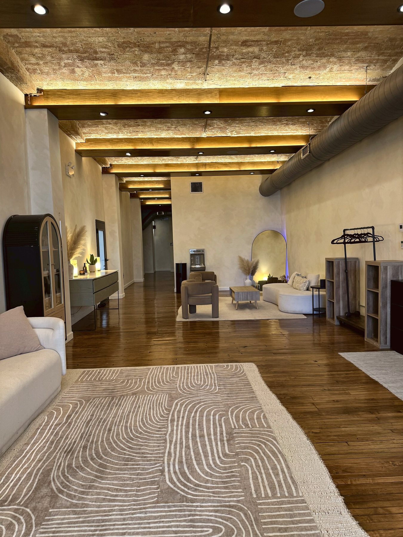 The Yoga 2.0 lounge and seating area in River North, Chicago, with exposed brick ceilings, hardwood floors, and an arched mirror, available for private events
